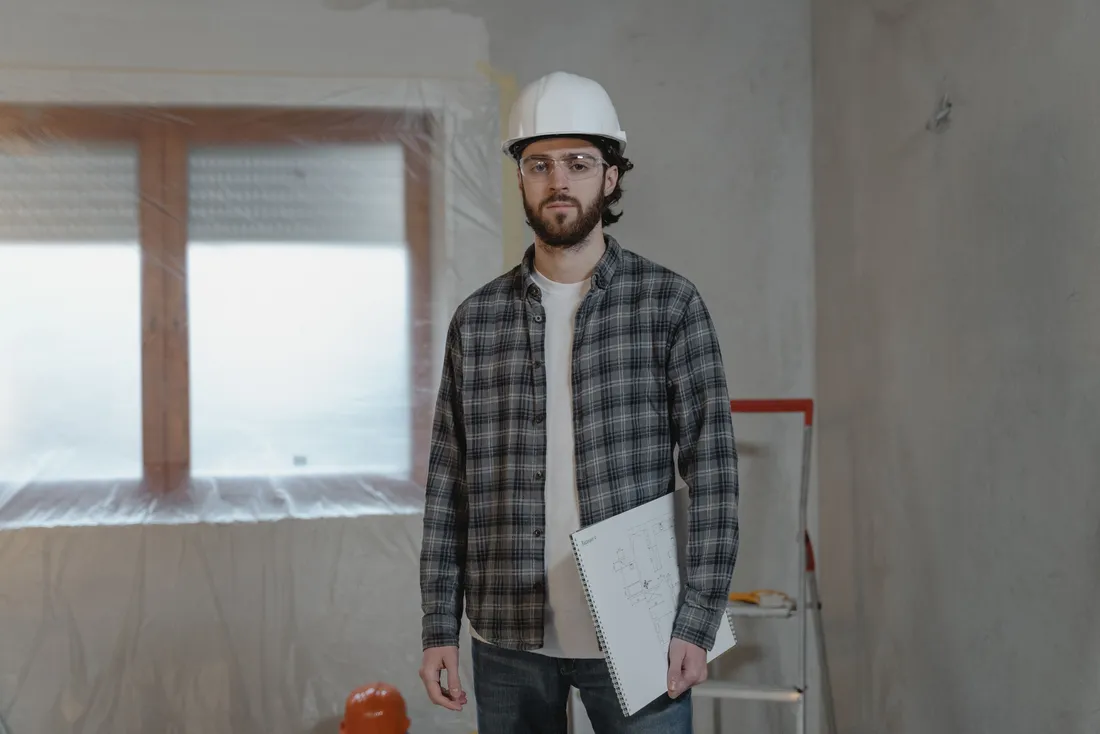 Artisan avec les plans du projet dans une pièce en travaux (Canohès, Pyrénées-Orientales)